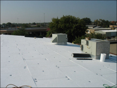 Installing a new TPO membrane over a metal flat roof (mid-process) on an industrial building in Wisconsin